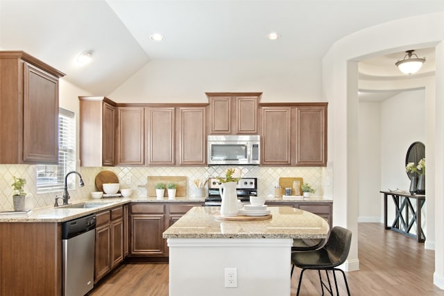 231 Archer Way, Forney, TX 75126 - kitchen with a breakfast bar, a sink, stainless steel appliances, light wood-style floors, and light stone countertops