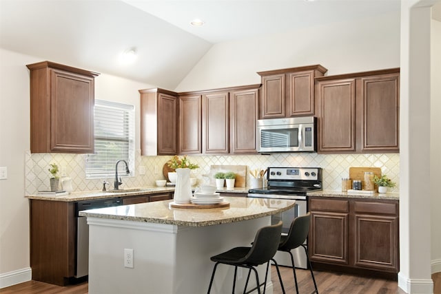 231 Archer Way, Forney, TX 75126 - kitchen featuring a breakfast bar area, a sink, vaulted ceiling, dark wood-type flooring, and appliances with stainless steel finishes