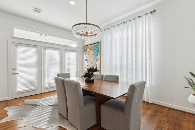 dining space featuring a chandelier, visible vents, baseboards, and wood finished floors