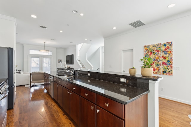 kitchen featuring open floor plan, wood finished floors, visible vents, and a spacious island