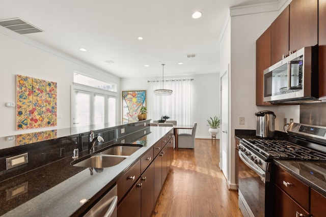 kitchen featuring light wood finished floors, visible vents, dark stone countertops, appliances with stainless steel finishes, and a sink