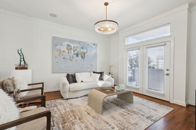 living area with crown molding, wood finished floors, baseboards, and a chandelier