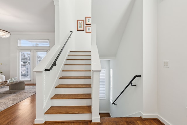 stairs with wood finished floors, baseboards, and a chandelier