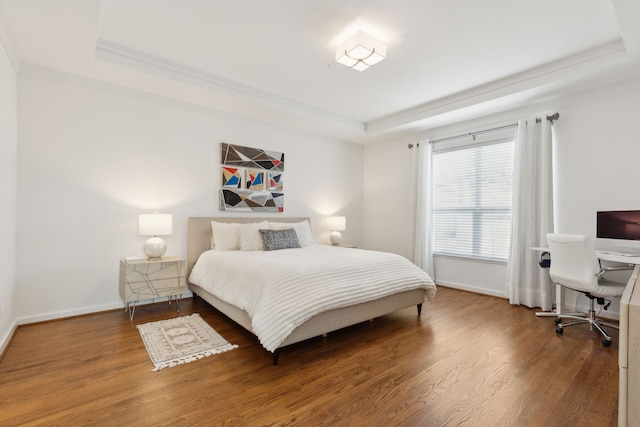 bedroom with a tray ceiling, baseboards, wood finished floors, and crown molding