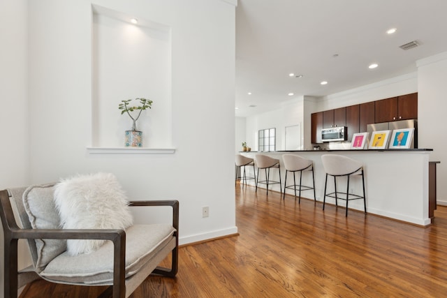 living area with visible vents, recessed lighting, baseboards, and wood finished floors