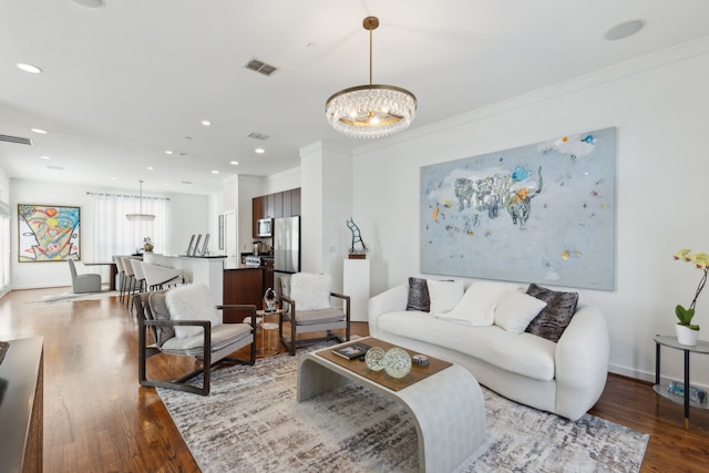 living room featuring visible vents, ornamental molding, wood finished floors, recessed lighting, and an inviting chandelier