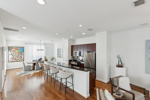 kitchen with a kitchen breakfast bar, wood finished floors, visible vents, and appliances with stainless steel finishes