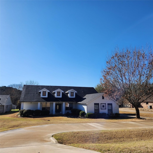 view of front of home featuring curved driveway, a front lawn, and stucco siding