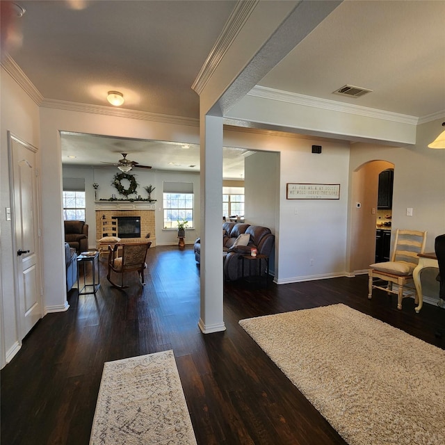 foyer featuring visible vents, ceiling fan, dark wood finished floors, a fireplace, and arched walkways