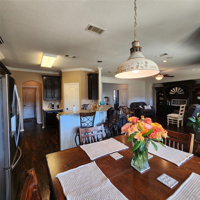 dining space with arched walkways, visible vents, and dark wood-style floors