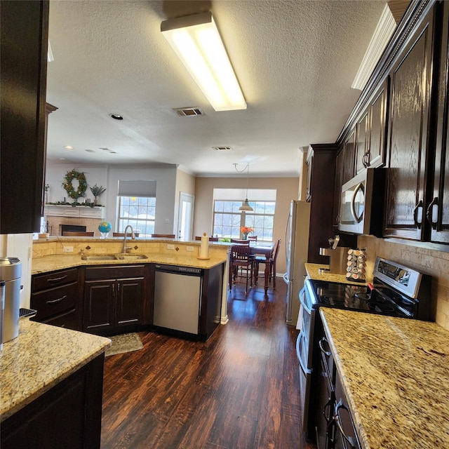 kitchen featuring visible vents, dark wood-type flooring, light stone countertops, stainless steel appliances, and a sink