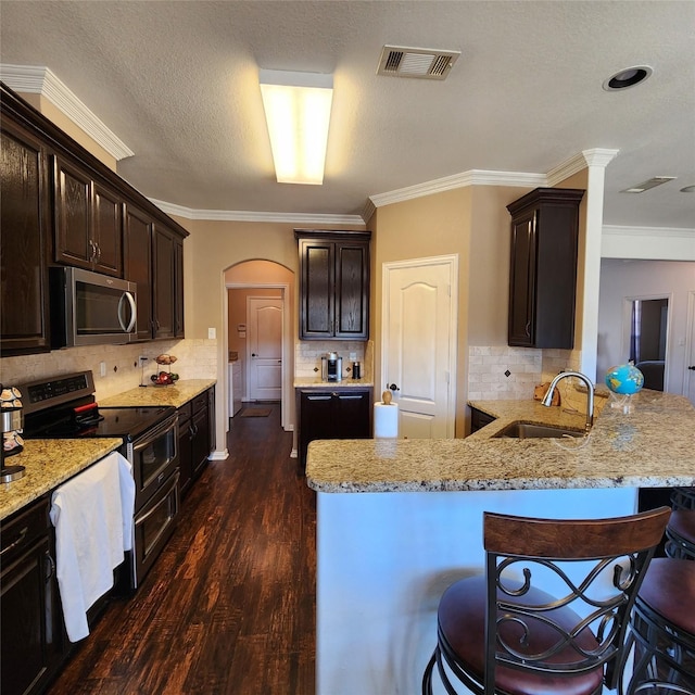 kitchen with visible vents, dark wood finished floors, arched walkways, a sink, and stainless steel appliances