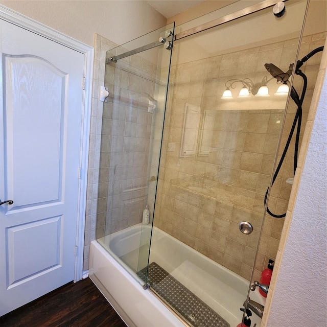 full bath with shower / bath combination with glass door and wood finished floors