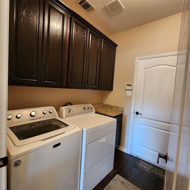 washroom featuring washing machine and clothes dryer, visible vents, cabinet space, and dark wood finished floors