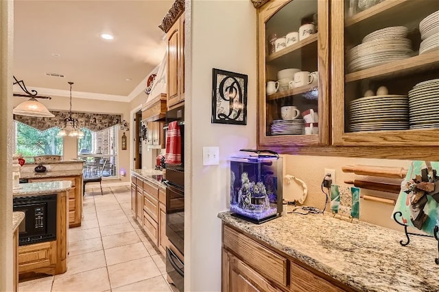 kitchen featuring light stone countertops, light tile patterned flooring, black microwave, pendant lighting, and crown molding