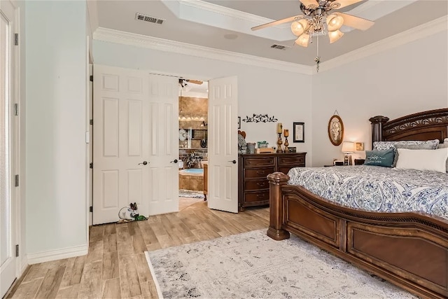 bedroom with crown molding, a tray ceiling, visible vents, and light wood finished floors