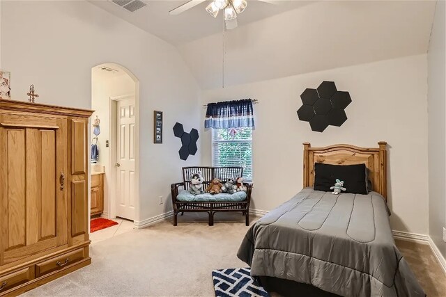 bedroom featuring light carpet, lofted ceiling, ensuite bath, arched walkways, and baseboards