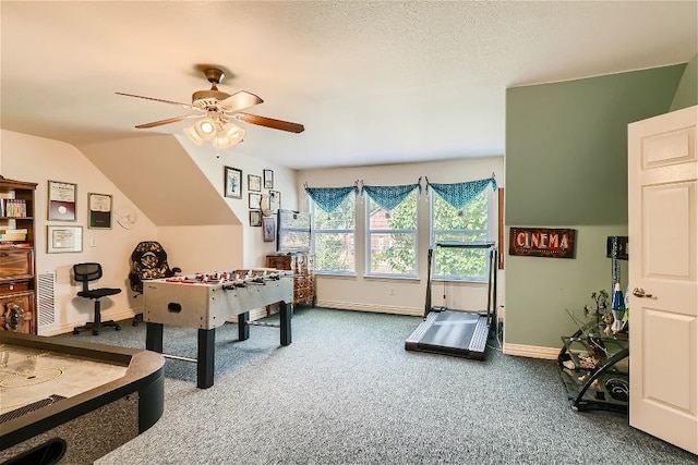 game room featuring a ceiling fan, carpet, baseboards, vaulted ceiling, and a textured ceiling