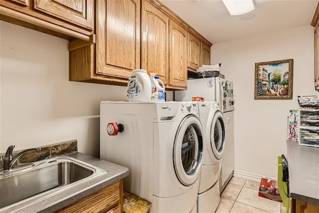 laundry area featuring light tile patterned floors, baseboards, cabinet space, a sink, and washer and dryer