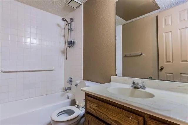 6743 Westcreek Dr, Fort Worth, TX 76133 - full bath with tub / shower combination, toilet, vanity, a textured wall, and a textured ceiling