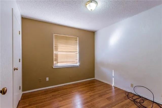 6743 Westcreek Dr, Fort Worth, TX 76133 - unfurnished room featuring wood finished floors, baseboards, and a textured ceiling