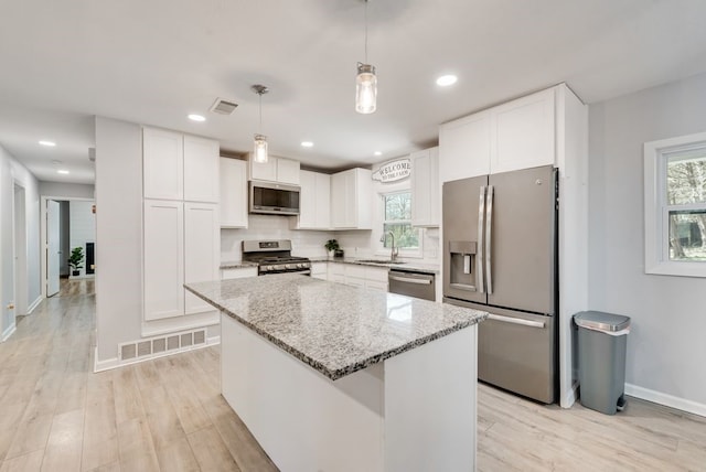 kitchen featuring light stone countertops, visible vents, backsplash, and stainless steel appliances