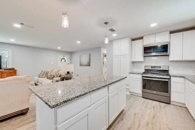 kitchen with light wood finished floors, visible vents, stainless steel appliances, and open floor plan