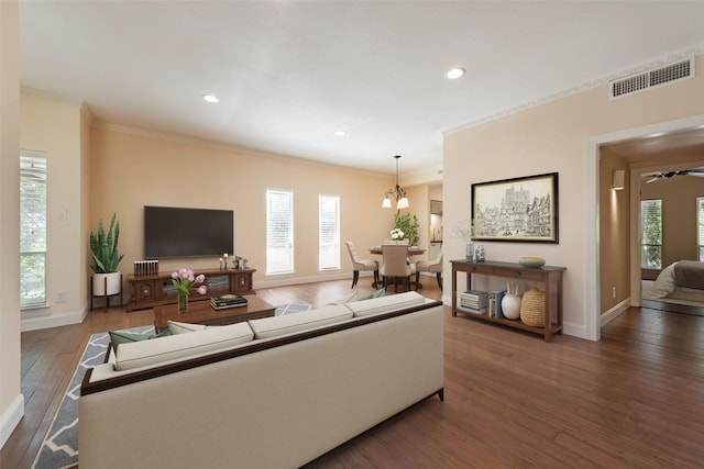 living area with visible vents, crown molding, baseboards, and wood finished floors