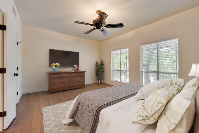 bedroom with a ceiling fan, baseboards, visible vents, and wood-type flooring