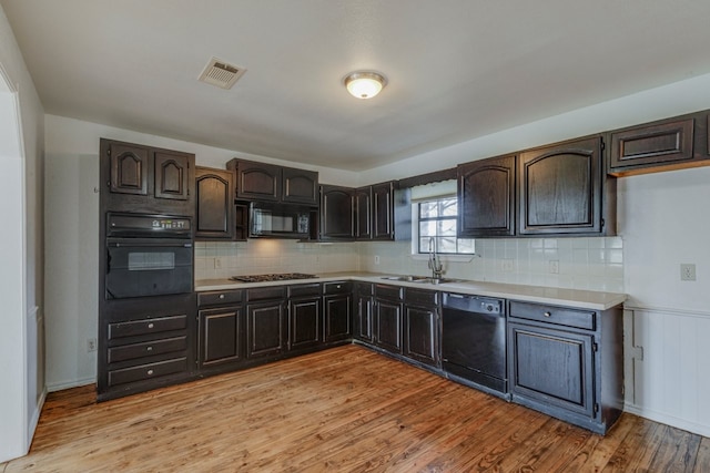 kitchen with visible vents, light wood-type flooring, black appliances, a sink, and light countertops