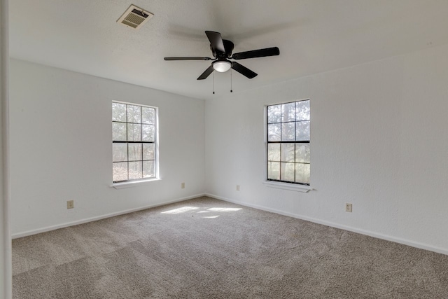 carpeted spare room with visible vents, a ceiling fan, and baseboards