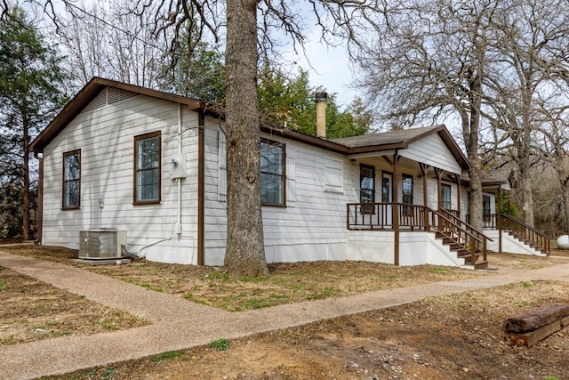 view of side of home with cooling unit, a porch, and a chimney