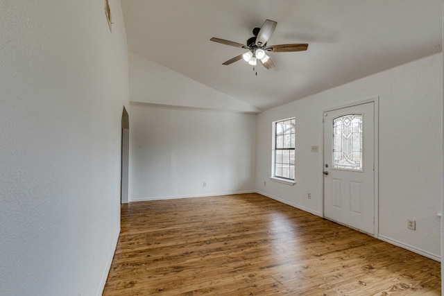 entrance foyer with a ceiling fan, wood finished floors, baseboards, lofted ceiling, and arched walkways