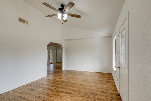 spare room with wood finished floors, plenty of natural light, visible vents, and arched walkways