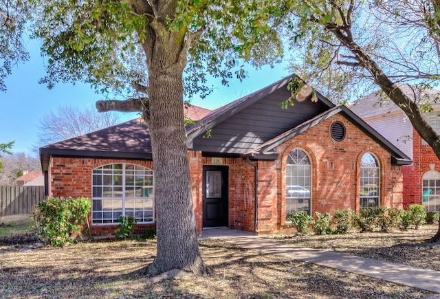 view of front of home featuring brick siding and fence