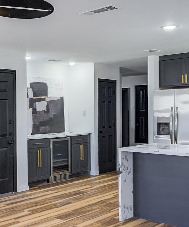 kitchen featuring light wood-style floors, visible vents, beverage cooler, and stainless steel refrigerator with ice dispenser