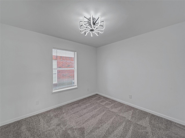 spare room with a notable chandelier, carpet flooring, and baseboards