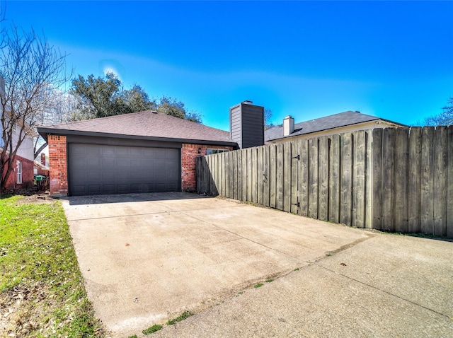 exterior space featuring a garage, brick siding, and fence