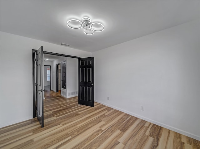 empty room with visible vents, baseboards, and light wood-style flooring