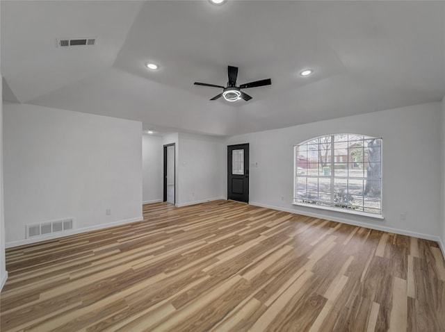 spare room featuring a raised ceiling, light wood-style flooring, and visible vents