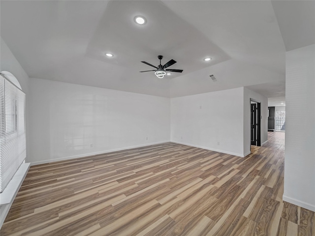 spare room featuring visible vents, baseboards, lofted ceiling, ceiling fan, and light wood-type flooring