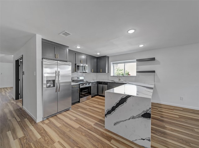 kitchen featuring light wood finished floors, visible vents, decorative backsplash, stainless steel appliances, and a sink