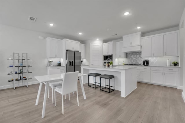 kitchen featuring visible vents, a sink, a kitchen breakfast bar, stainless steel appliances, and decorative backsplash