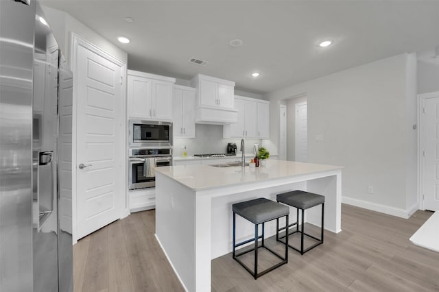 kitchen with light countertops, white cabinets, light wood-style floors, and stainless steel appliances