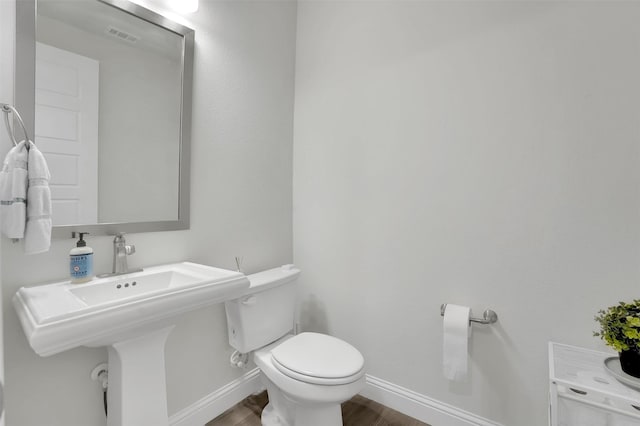 bathroom featuring visible vents, toilet, baseboards, and wood finished floors