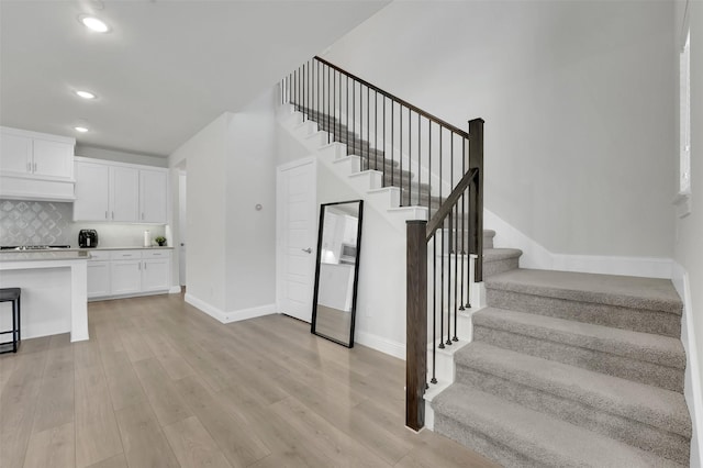 staircase featuring recessed lighting, baseboards, and wood finished floors