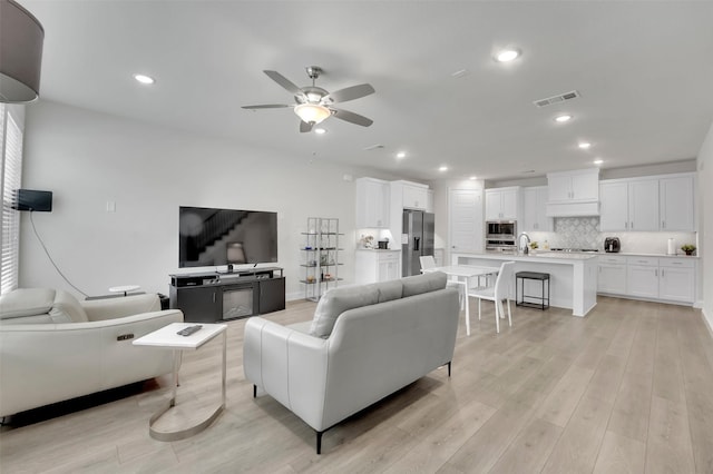 living area with recessed lighting, visible vents, light wood-style flooring, and a ceiling fan