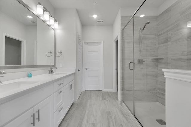 full bath featuring double vanity, visible vents, a stall shower, and a sink