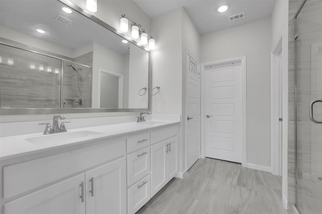 full bath with a sink, visible vents, a stall shower, and double vanity