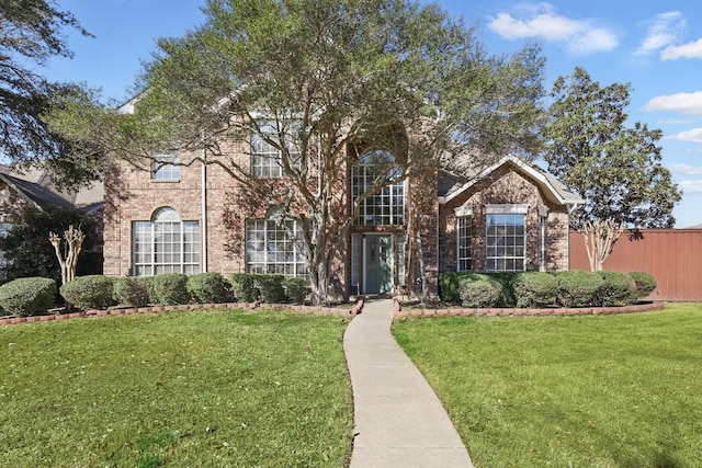 view of front of property featuring brick siding, a front yard, and fence